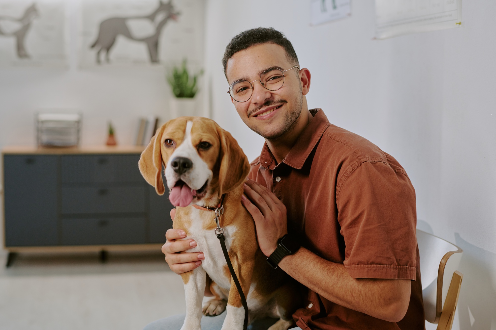 Portrait of Smiling Man Sitting and Holding Dog in Veterinary Office